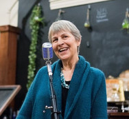woman standing in front of microphone wearing blue sweater