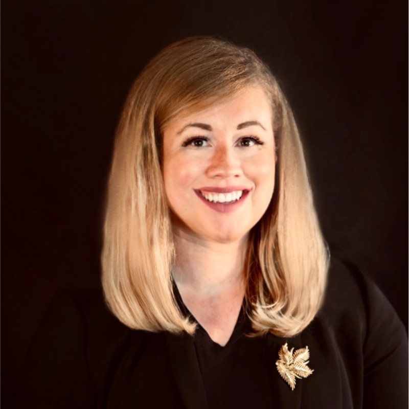 Headshot of a smiling woman with shoulder-length blond hair wearing a black shirt