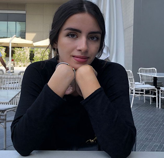 A young woman with her hands folded under her chin