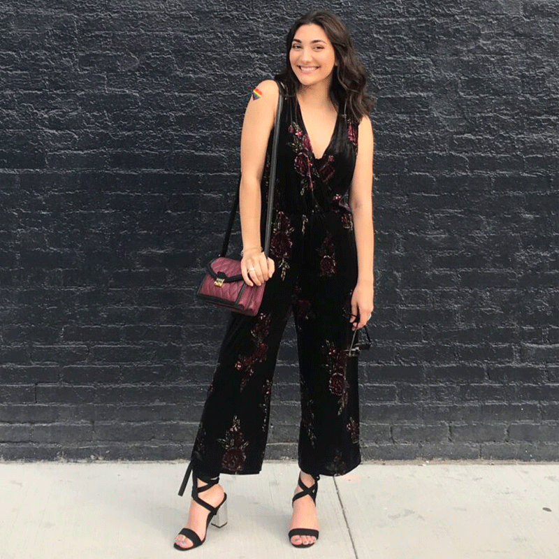 A woman in a dressy black outfit holding a handbag