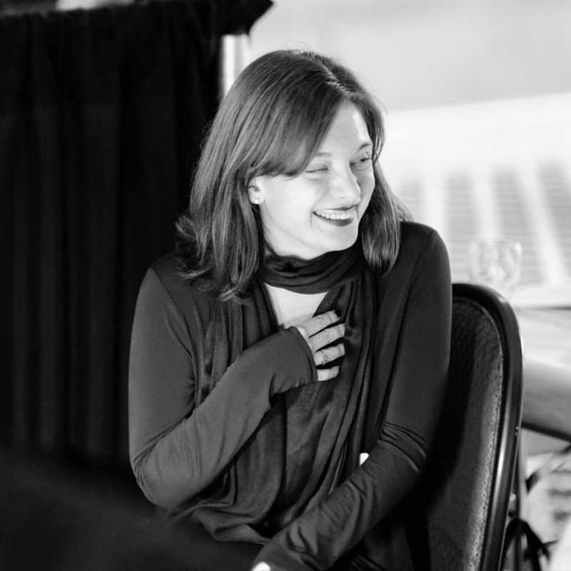 Black-and-white image of a woman with shoulder-length hair looking to the side and wearing a scarf