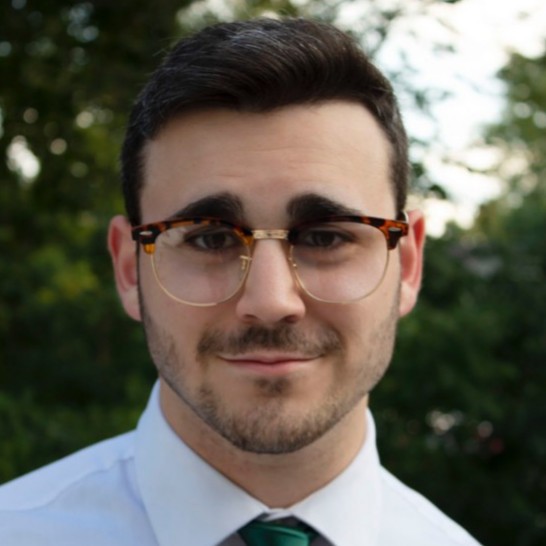 Headshot of a man with dark hair and glasses in a shirt and tie