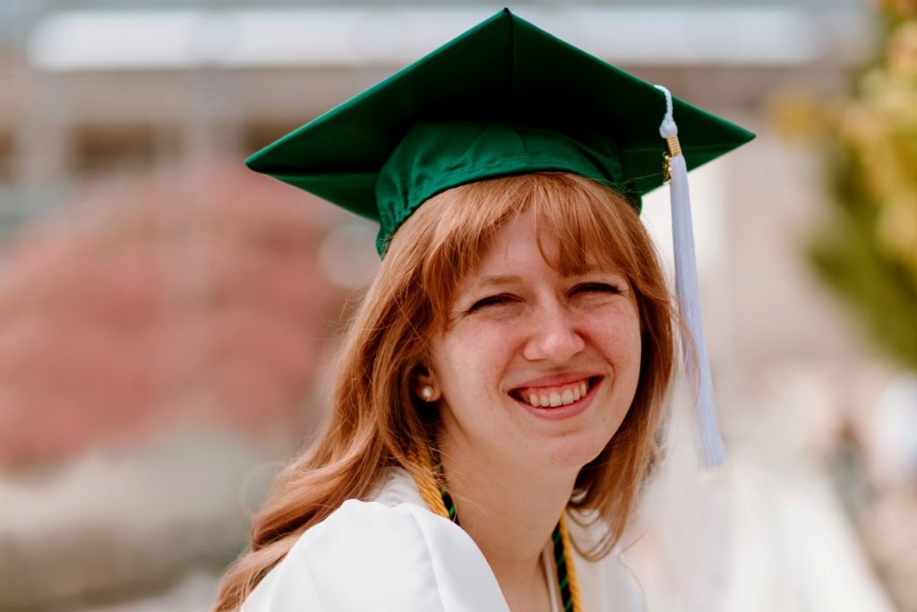 A portrait of Hillary Hemry in a green graduation cap.