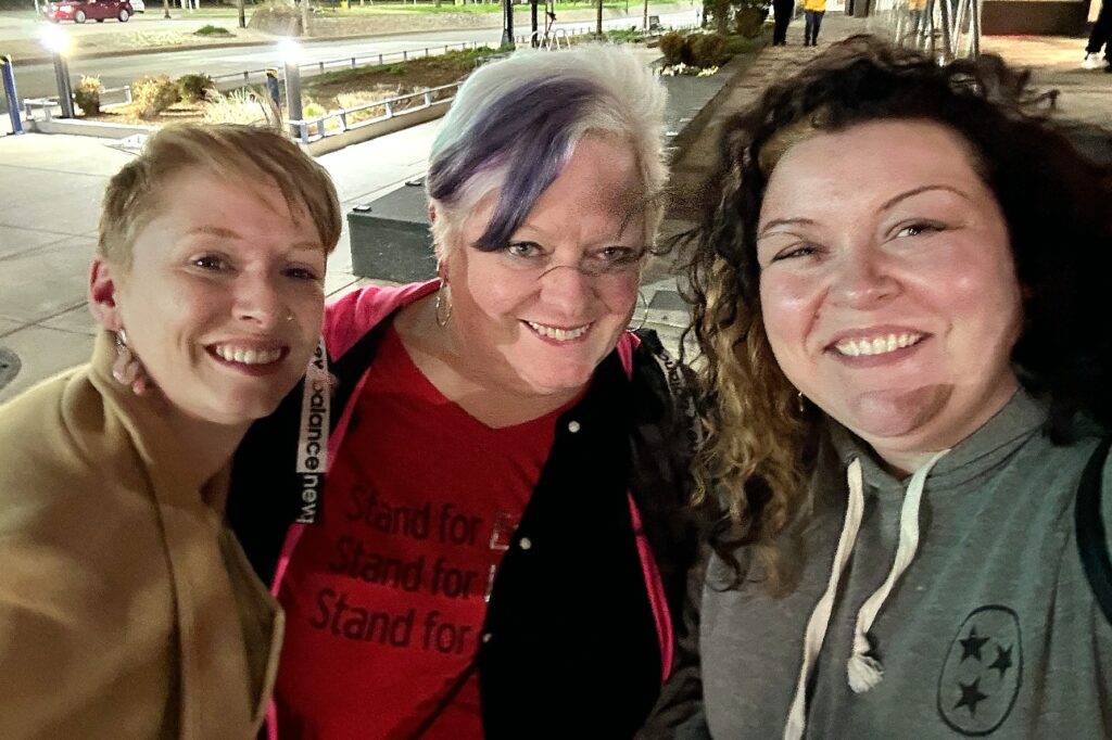 A selfie photo of three women who are all smiling at the camera.