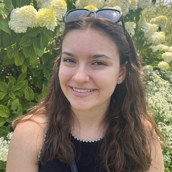 smiling woman with sunglasses on top of her head standing in front of a flowering tree