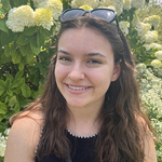 smiling woman with sunglasses on top of her head standing in front of a flowering tree