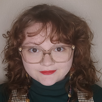 smiling woman with red curly hair wearing glasses