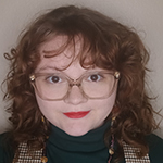 smiling woman with red curly hair wearing glasses