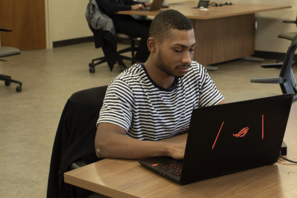 An African-American student typing on a laptop