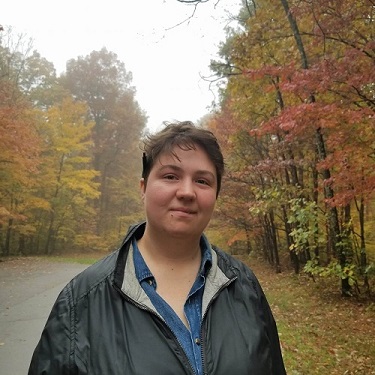 woman with short hair walking through a forest