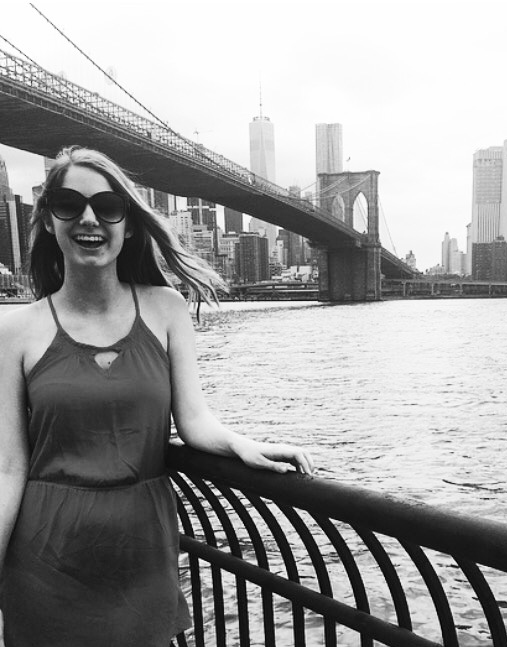 woman posing for picture in front of brooklyn bridge