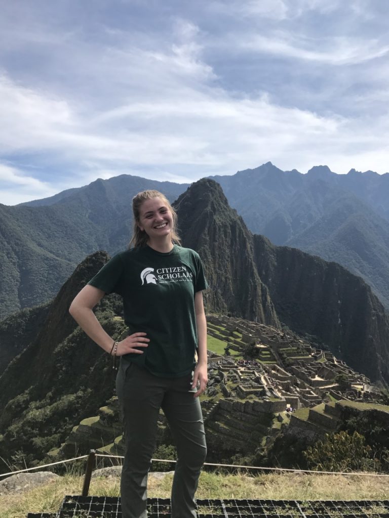 a girl standing on the mountain wearing a green shirt 