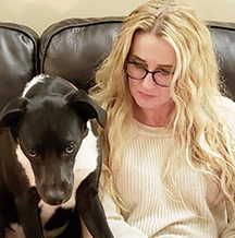 woman with glasses sitting next to dog