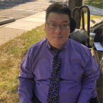 A man with dark hair wearing a purple shirt