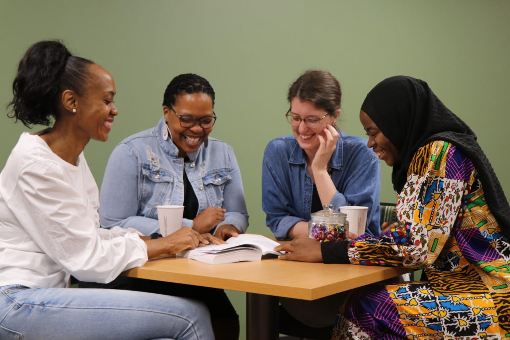 A diverse group of students laugh together over a book